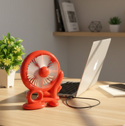 Cart shape USB mini fan on a wooden desk next to a laptop