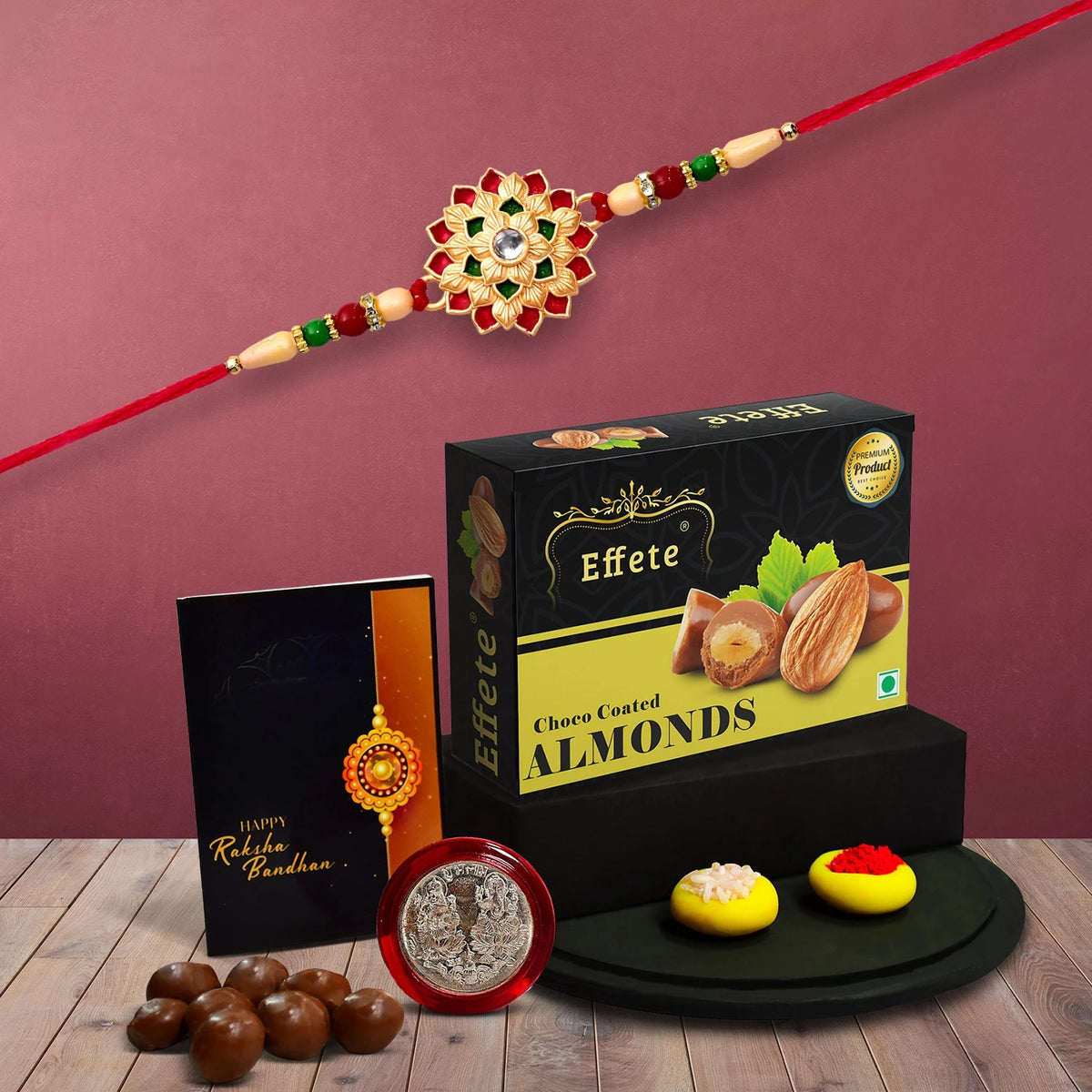 A premium Rakhi Gift Combo featuring a floral rakhi, silver coin, and chocolate almonds.