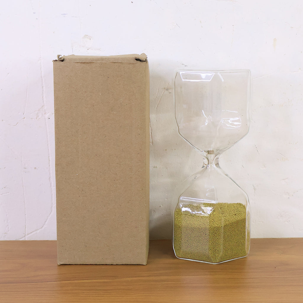 Faceted glass hourglass sand timer with golden sand, packed and shown upright