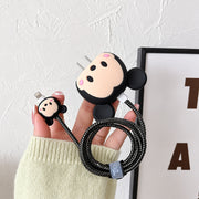 A hand holds a black Mickey Mouse character charger cover with a black cable protector and small matching connector cover.