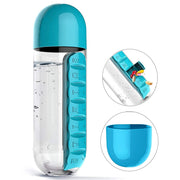 Transparent water bottle featuring a blue lid and a side-mounted blue pill dispenser, shown with water and tablets.