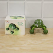 A green turtle massager stands beside its white and green product box on a light wooden surface.