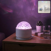 White projection light with a clear textured dome, casting purple light onto a wall, on a wooden nightstand.