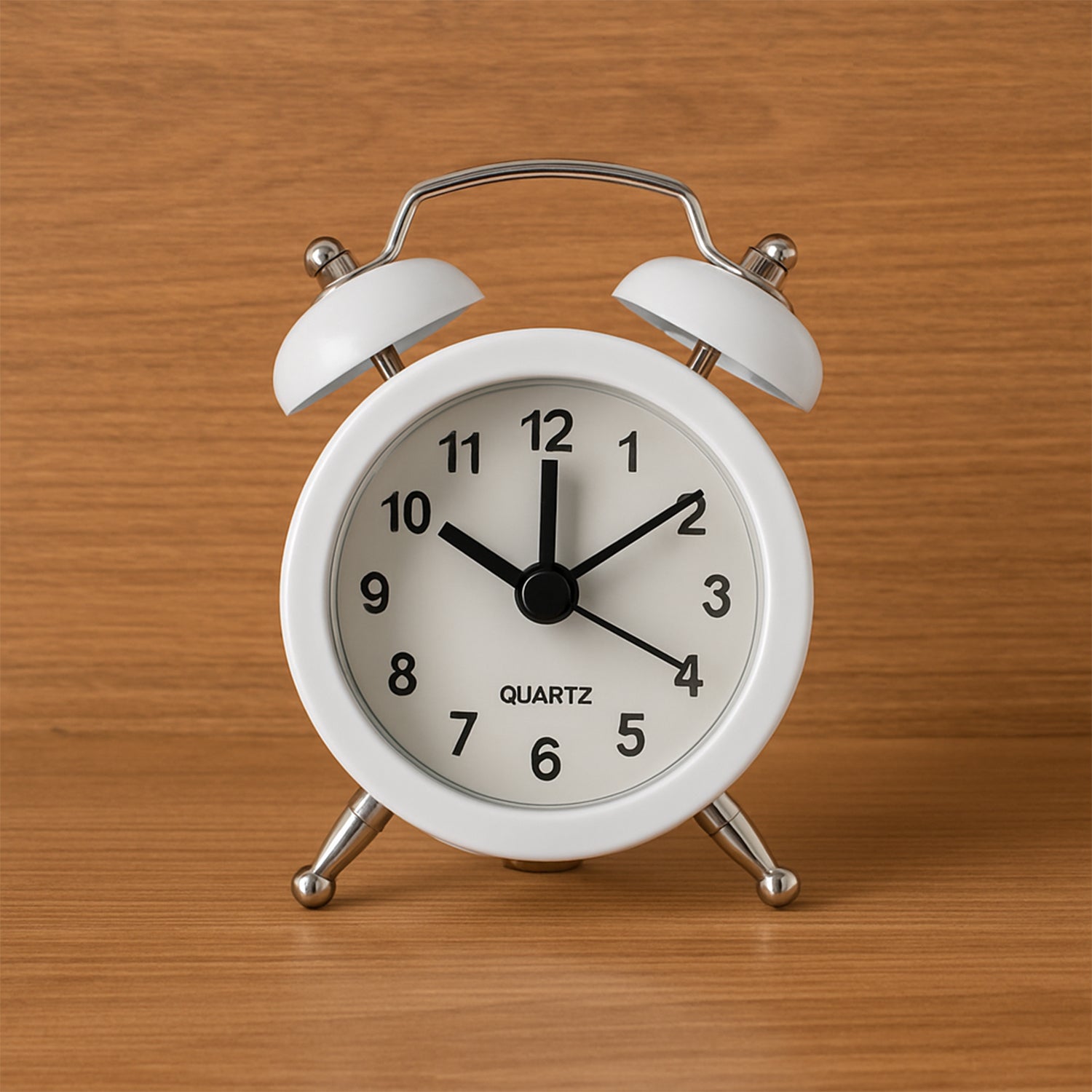 Twin-bell alarm clock on a bedside table with a book