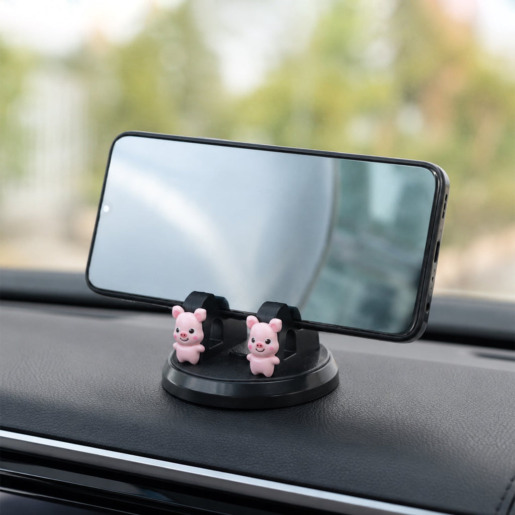 A black phone holder with two pink pig figurines on a car dashboard, holding a smartphone 
