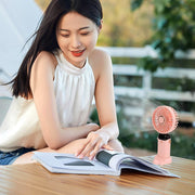 A person holding the compact rechargeable portable fan for personal cooling.