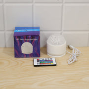 White dome projection light, its blue box, and a remote control on a light wooden surface.