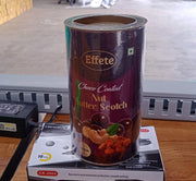 A purple and gold can of choco-coated nut butterscotch stands on a white box, with a black power adapter nearby on a wooden