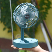 A four-panel image shows the dark green fan in various settings: on a desk, next to a chair, with a family, and in a car.
