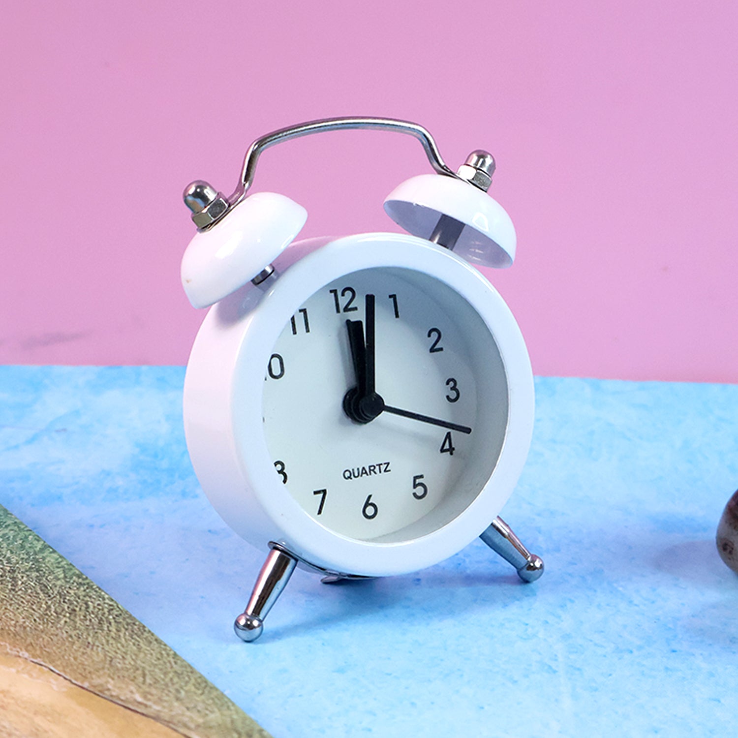 Twin-bell alarm clock in hand, showing its compact size