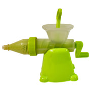 Lime green and translucent manual juicer with a handle, in front of its product box on a green textured surface.