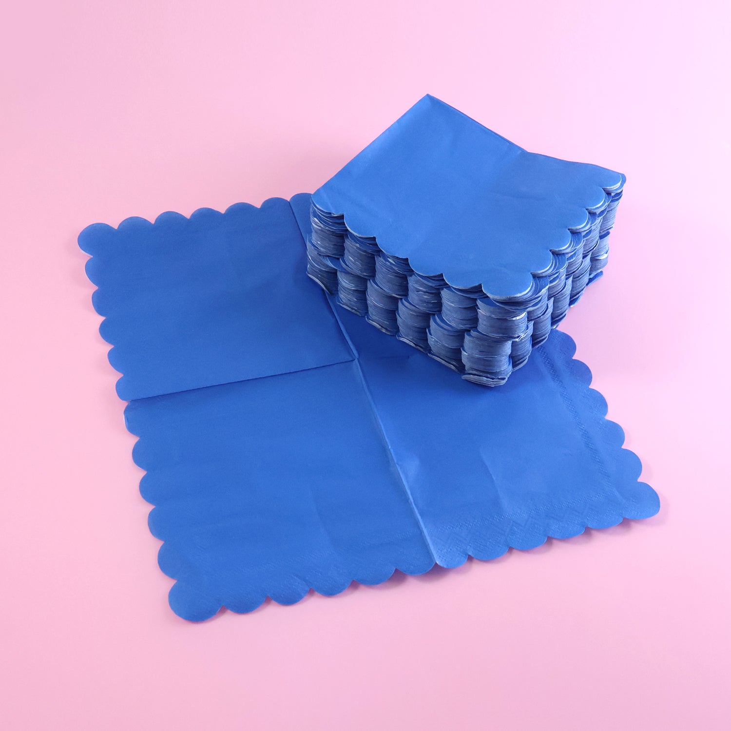 Stack of royal blue scalloped disposable napkins, showing texture