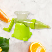 Lime green and translucent manual juicer with a handle, surrounded by various fruits and vegetables on a white background.