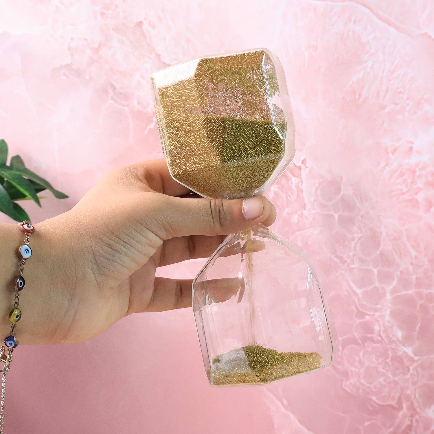 Side view of faceted glass hourglass sand timer with golden sand